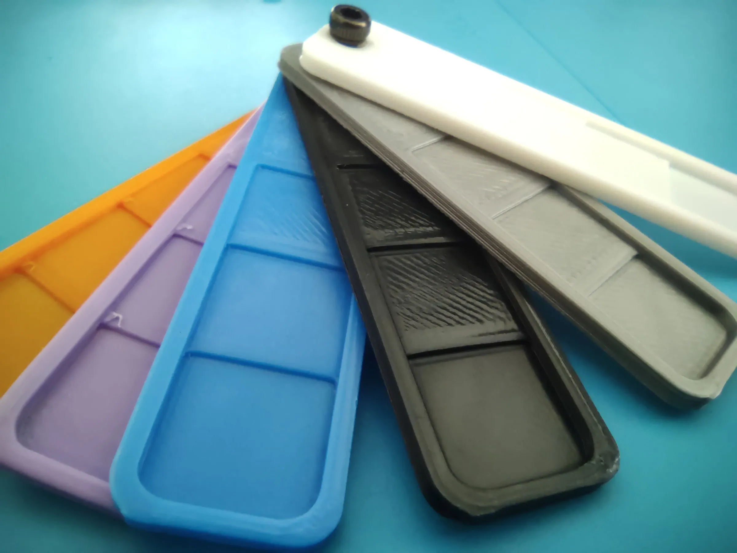 six printed filament swatches in different colours fanned out on one screw